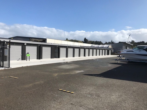 An outside area with a line of self storage units on one side with the shutters down.