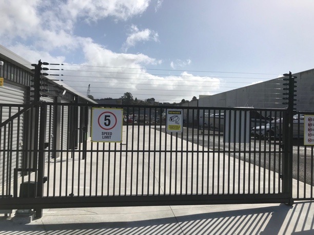 a large metal gate, the other side of which is a yard in a storage facility