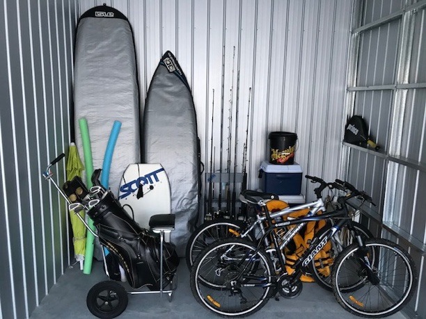 inside a self storage locker, with surfboards, bikes and a golf bag in view