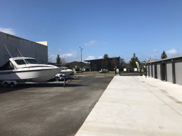 an outside setting with a boat parked on the left and storage units on the right