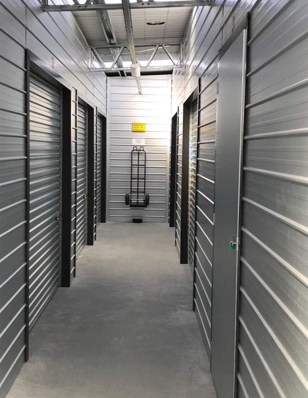 a narrow corridor with closed shutters in a self storage setting