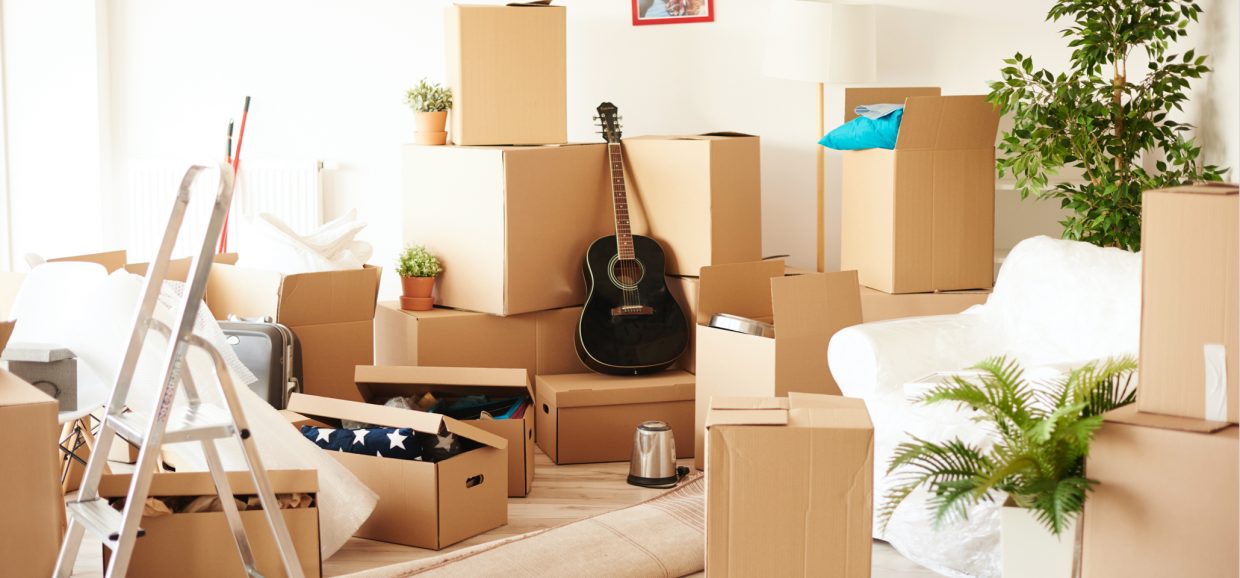 boxes packed in a house with a sofa, stepladder and a guitar in view
